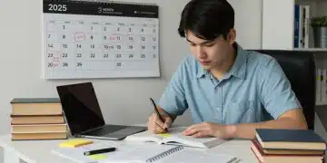 Student diligently studying with textbooks and laptop for US standardized exams 2025